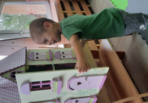 Chłopiec bawi się domkiem dla lalek